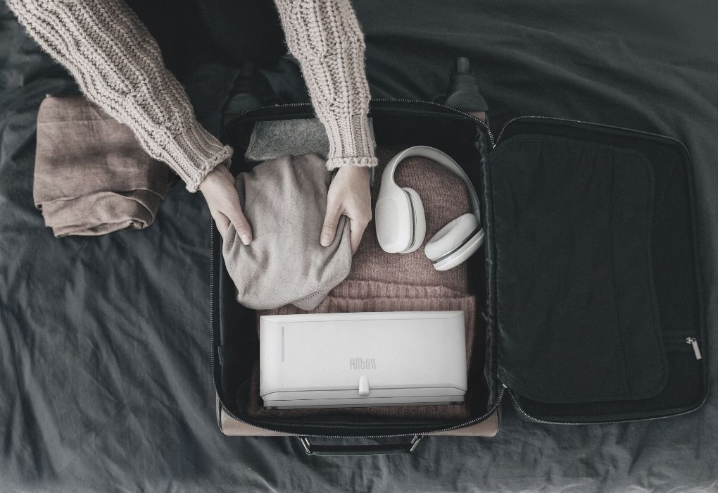 AllBliss in a open suitcase packed with clothes and a headphone.